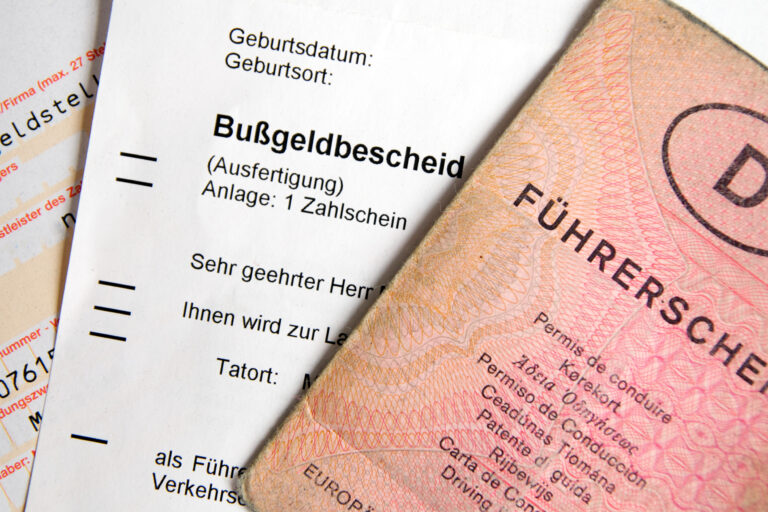 Close-up of a German Bußgeldbescheid fine notice overlapped by a pink euro banknote on the right side.